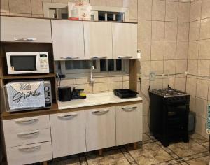 uma cozinha com armários brancos, um micro-ondas e um fogão em Casa de férias! em Capão da Canoa