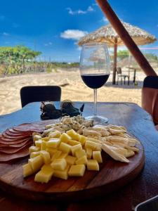 a plate of cheese and a glass of wine on a table at Pacas Suítes Casa & Chalés in Santo Amaro