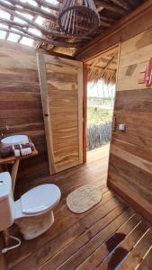 a wooden bathroom with a toilet and a door at Kitesurf Life Glamping in Tutóia