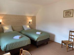 two twin beds in a room with a chair at Les gites de l'Abeaupinière in Reboursin