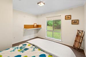 Schlafzimmer mit einem Bett und einem Fenster in der Unterkunft Basecamp Sawmill in Mount Buller