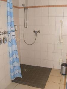 La salle de bains est pourvue d'une douche avec un rideau de douche bleu et blanc. dans l'établissement Strandläufer Classic 106, à Granzow