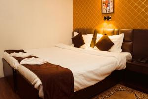 een slaapkamer met een bed met witte lakens en kussens bij Hotel Siddhi Vinayak Regency, Mg Marg in Gangtok