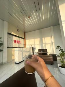 uma pessoa segurando um copo de bebida numa sala de estar em KBI Hostel em Ternate