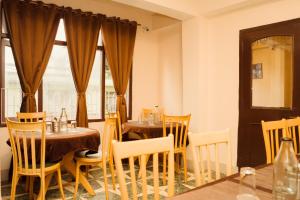 een eetkamer met 2 tafels, stoelen en ramen bij Hotel Siddhi Vinayak Regency, Mg Marg in Gangtok