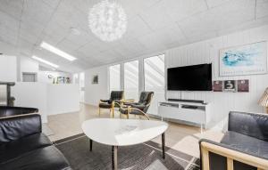 HavrvigにあるNice Home In Hvide Sande With Saunaのリビングルーム(テレビ、テーブル、椅子付)