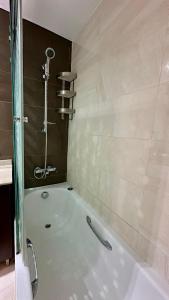 a bathroom with a bath tub with a shower at hilton apartement families in Tangier