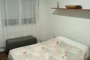 a bedroom with a bed and a stool and a window at Apto Centrico Zona Tres Cruces in Montevideo