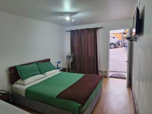 Un dormitorio con una cama con sábanas verdes y una ventana en Hosteria Piedra Blanca, en Taltal