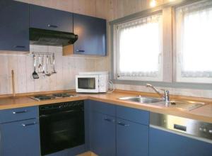 La cuisine est équipée de placards bleus, d'un évier et d'un four micro-ondes. dans l'établissement Seeschwalbe 99, à Mirow