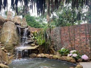 einen Wasserfall in einem Garten mit einer Steinmauer in der Unterkunft Pu Luong Paradise in Hương Bá Thước