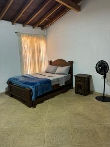 a bedroom with a bed and a window and a fan at FINCA VILLA LORA GIRARDOTA in Girardota