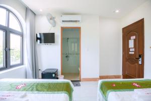 ALEX HOTEL AND SPA في An Bàn: غرفة بسريرين وتلفزيون وباب