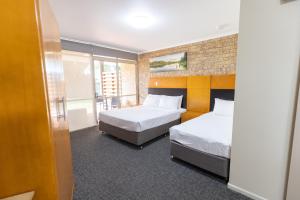 a hotel room with two beds and a balcony at Sundowner Hotel Motel in Caboolture