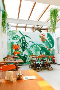 a room with tables and a mural of plants at Palace Beach Hostel in Rio de Janeiro