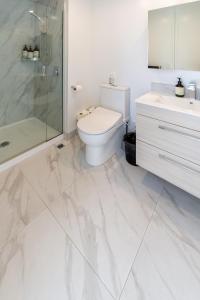 a white bathroom with a toilet and a shower at Stadium Suite - CBD in Christchurch +17 photos