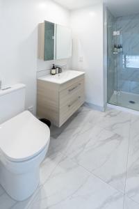 a bathroom with a toilet and a sink and a shower at Stadium Suite - CBD in Christchurch