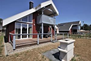 ein Haus mit einer großen Holzterrasse in einem Hof in der Unterkunft Seeschwalbe Classic 309 in Mirow