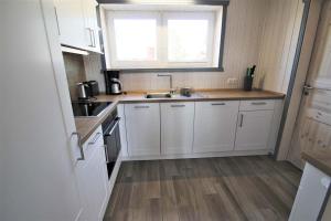 a kitchen with white cabinets and a sink and a window at Seeschwalbe Classic 310 in Mirow