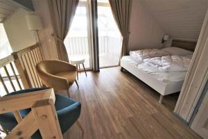 a bedroom with a bed and a chair and a balcony at Seeschwalbe Classic 310 in Mirow