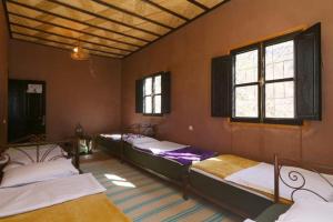 a room with three beds in it with windows at Locanda Lodge, Marrakech Tacheddirt in Marrakech