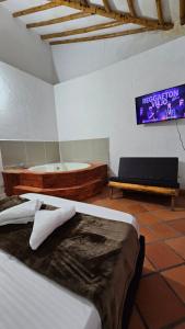 Habitación con 2 camas y TV en la pared. en HOSTERÍA BRISAS DEL RÍO, en Marinilla