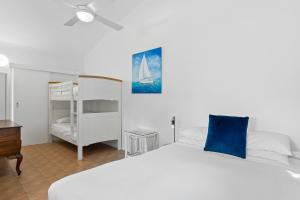 um quarto com uma cama branca e uma almofada azul em The Little Blue Shack - Quaint Granny Flat em Bli Bli