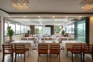 a restaurant with white tables and chairs and windows at The Light Hotel in Hanoi