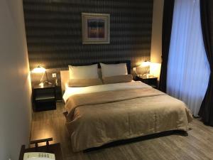 RazgradにあるHotel Mimozaのベッドルーム1室(大型ベッド1台、テーブル上のランプ2つ付)