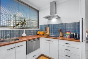 a kitchen with white cabinets and blue tiles at Stylish Riverside 1Bed/Studio with Rooftop Pool in Brisbane