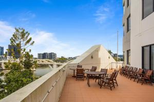 a balcony with tables and chairs on a building at Stylish Riverside 1Bed/Studio with Rooftop Pool in Brisbane