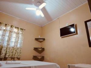 1 dormitorio con ventilador de techo y TV en la pared en Pouso Trindade en Trindade