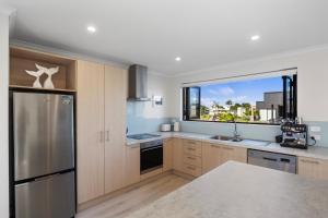 a kitchen with a stainless steel refrigerator and a window at Modern Family Bach - Waihi Beach Holiday Home in Waihi