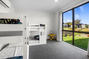 a bedroom with bunk beds and a large window at Modern Family Bach - Waihi Beach Holiday Home in Waihi