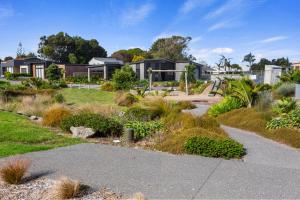 a garden with houses in the background at Modern Family Bach - Waihi Beach Holiday Home in Waihi