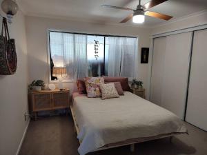 Schlafzimmer mit einem Bett mit Kissen und einem Deckenventilator in der Unterkunft McMansion: Sleeps 6, Walk to Beach, Pet Friendly in Golden Beach