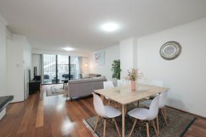 a living room with a wooden table and white chairs at Fantastic 3 Bds apartment Darling Harbour & Fish Market & Chinatown & Casino & Central in Sydney