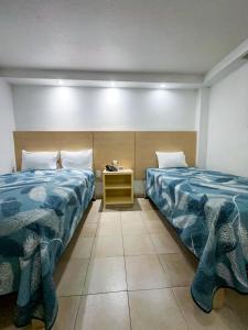 a room with two beds and a nightstand between them at Hotel Nueva Zelanda in León