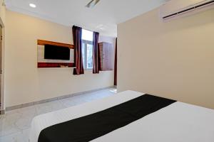 um quarto com uma cama e uma televisão na parede em OYO Hotel Leela Elite em Vijayawada