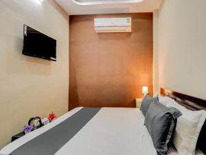 um quarto com uma cama e uma televisão na parede em OYO HOTEL ORR RESIDENCY em Hyderabad