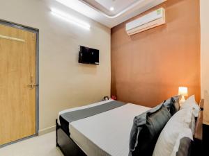 um quarto com uma cama e uma televisão na parede em OYO HOTEL ORR RESIDENCY em Hyderabad