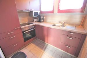 a kitchen with red cabinets and a sink at Wildgans 41 in Mirow +6 photos