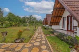 a cobblestone path next to a house and a field at Maskot Penida Cottage in Nusa Penida