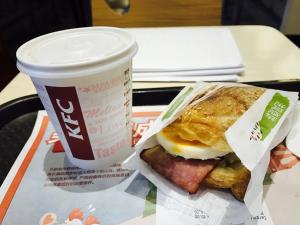 a breakfast sandwich and a cup of coffee on a tray at Wind sleeping Color Hotel - GuangZhou CHIME LONG Line7&18Nancun Wanbo STN in Guangzhou