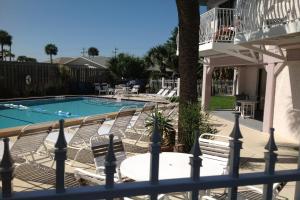 uma piscina com cadeiras, uma mesa e uma cerca em Ola Grande 218 em Cocoa Beach