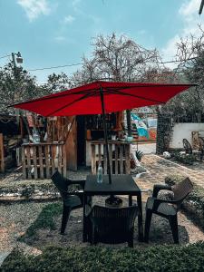 un ombrellone rosso seduto su un tavolo con sedie di Complejo Don Pascual a San Pedro La Laguna