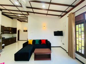 a living room with a black couch and a table at Tango Sunrise Villa in Tangalle