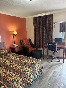 um quarto de hotel com uma cama, uma secretária e uma cadeira em Budget Inn - Scottsboro em Scottsboro