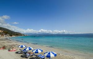 - une plage avec des parasols bleus et blancs et l'océan dans l'établissement Cozy Home In Piscia Rossa With Wifi, à Afa