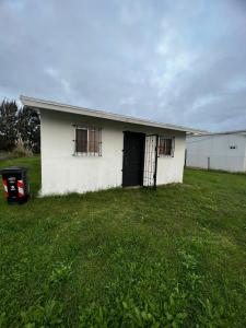 a white building with a black door in a field at Casa en El Pinar in Ciudad de la Costa